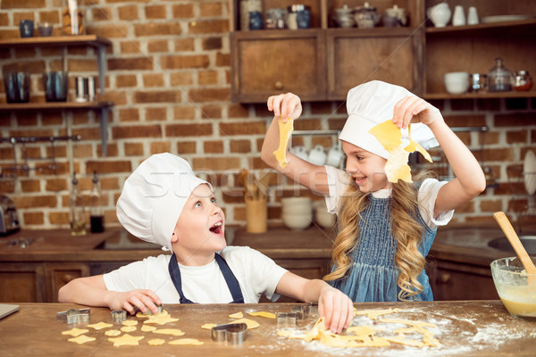 excited kids playing with dough for shaped cookies in kitchen Stock photo © LightFieldStudios