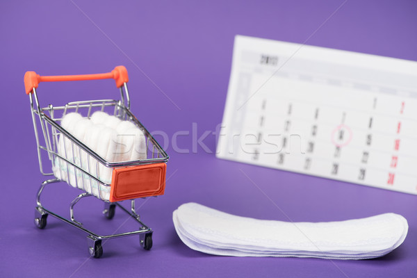 tampons in small shopping cart, daily liners and calendar on purple Stock photo © LightFieldStudios