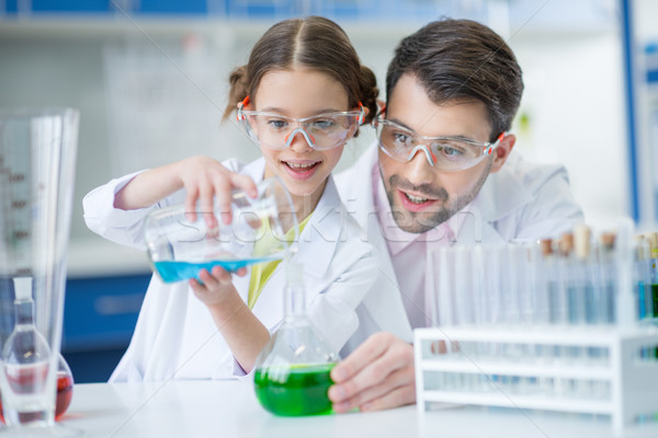 Stock photo: Teacher and student scientists in protective glasses making experiment in lab