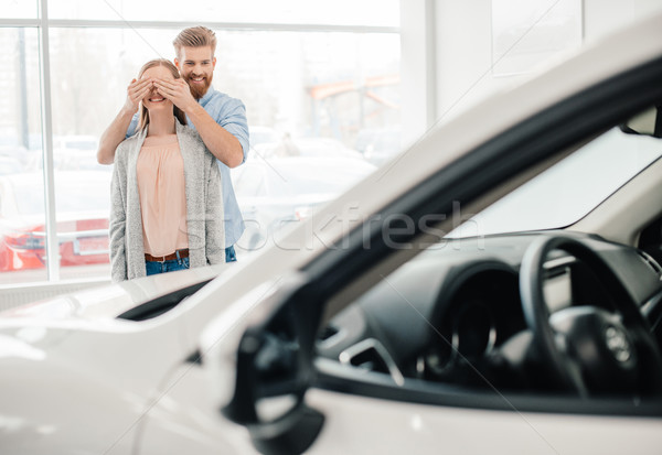 Man closing woman's eyes to make a surprise in dealership salon Stock photo © LightFieldStudios