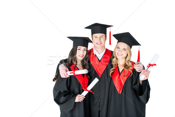 Happy students in academic caps standing embracing with diplomas and looking at camera    Stock photo © LightFieldStudios