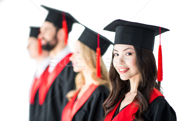 attractive student in graduation cap with diploma, with friends behind isolated on white Stock photo © LightFieldStudios