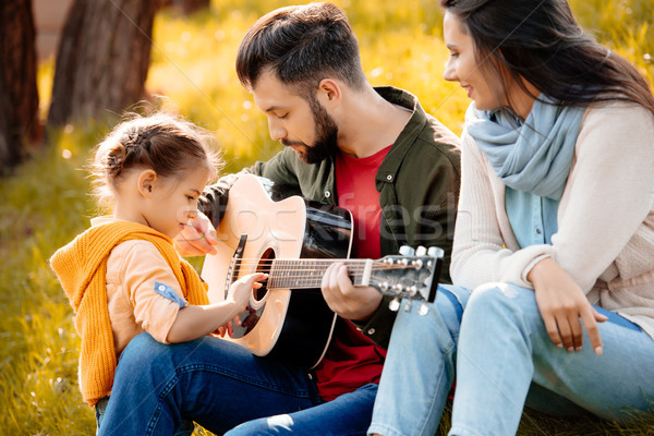 Young man playing guitar with family Stock photo © LightFieldStudios