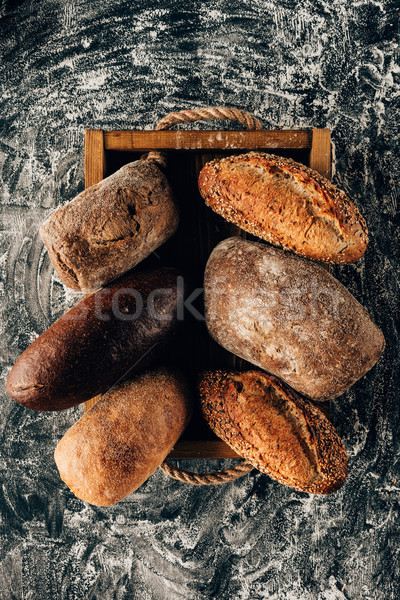 top view of arranged loafs of bread in wooden box on dark tabletop with flour Stock photo © LightFieldStudios