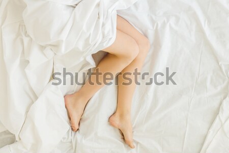 Stock photo: female feet stretching out of blanket