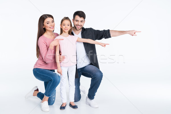 Happy young family with one child pointing away with fingers Stock photo © LightFieldStudios