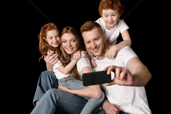 happy family taking selfie on smartphone isolated on black Stock photo © LightFieldStudios