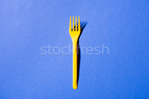 Stock photo: top view of yellow plastic fork isolated on violet