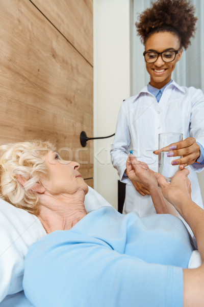 Doctor handing sick woman medicine Stock photo © LightFieldStudios