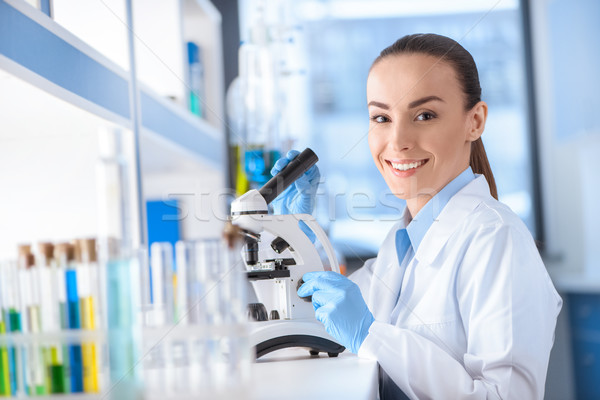 portrait of smiling scientist working with microscope and looking to camera Stock photo © LightFieldStudios