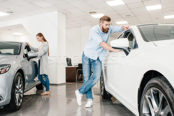 Couple choosing car, man and woman looking on various cars in dealership salon    Stock photo © LightFieldStudios