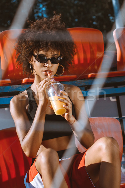 african-american woman in bleachers drinking juice Stock photo © LightFieldStudios