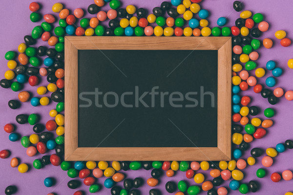 top view of candies and empty blackboard isolated on purple Stock photo © LightFieldStudios