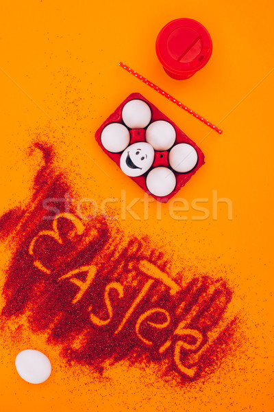 top view of easter sign made of red sand with chicken eggs with smiley on orange Stock photo © LightFieldStudios