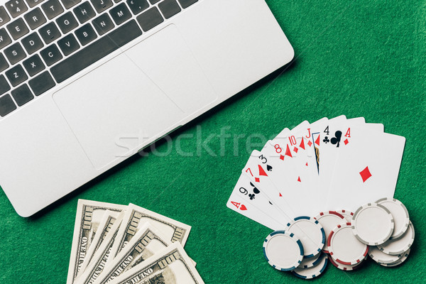 Online gambling concept with cards and money on table by laptop Stock photo © LightFieldStudios