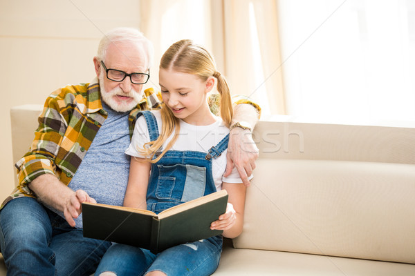 Smiling preteen girl with senior man in eyeglasses reading book together Stock photo © LightFieldStudios