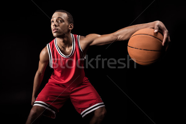 african sporty man in sports uniform playing basketball on black Stock photo © LightFieldStudios