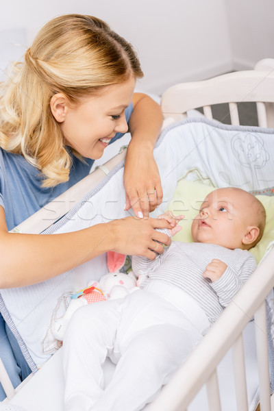 mother looking at baby in crib Stock photo © LightFieldStudios