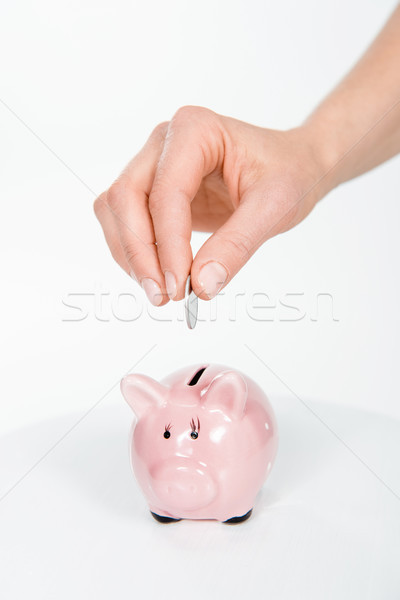 Cropped view of woman putting coin in piggy bank on white Stock photo © LightFieldStudios