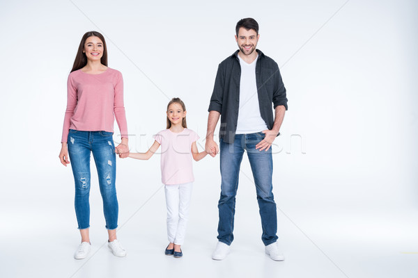 Happy young family with one child holding hands and smiling at camera  Stock photo © LightFieldStudios