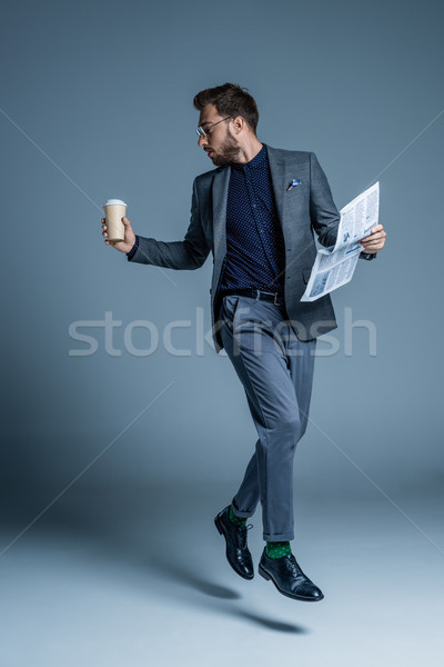 Businessman walking with coffee and newspaper Stock photo © LightFieldStudios