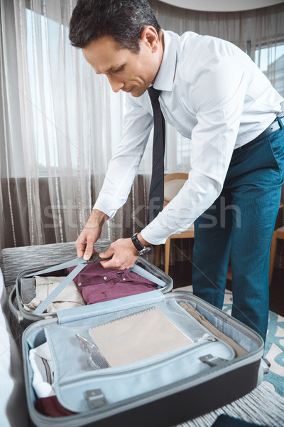 Businessman unpacking suitcase Stock photo © LightFieldStudios