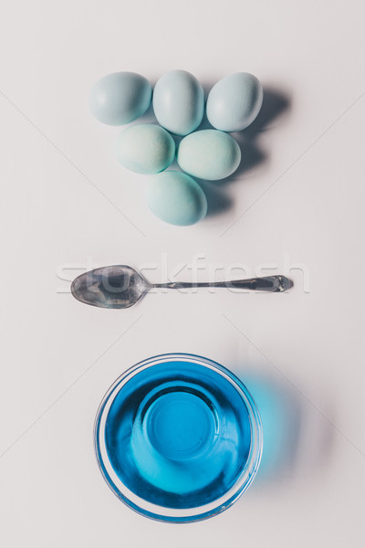 top view of glass with blue paint, spoon and chicken eggs on white surface, easter concept Stock photo © LightFieldStudios