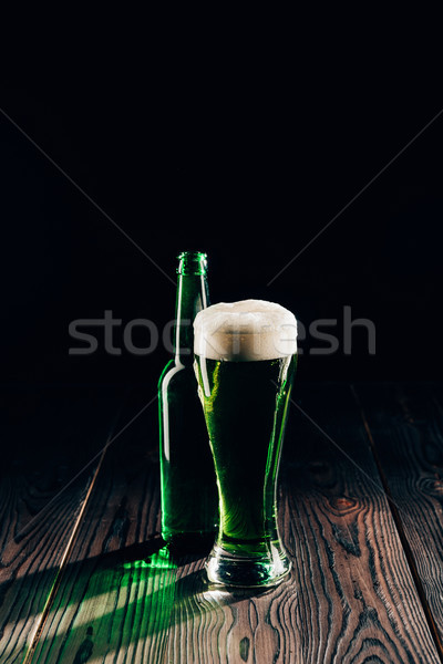 shining glass and bottle of green beer on wooden table, st patricks day concept Stock photo © LightFieldStudios