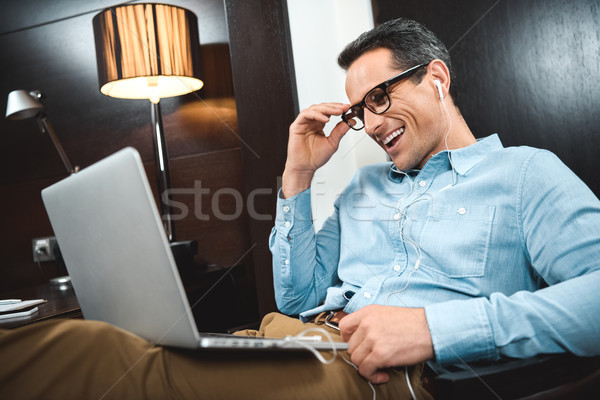 Laughing businessman in headphones using laptop Stock photo © LightFieldStudios