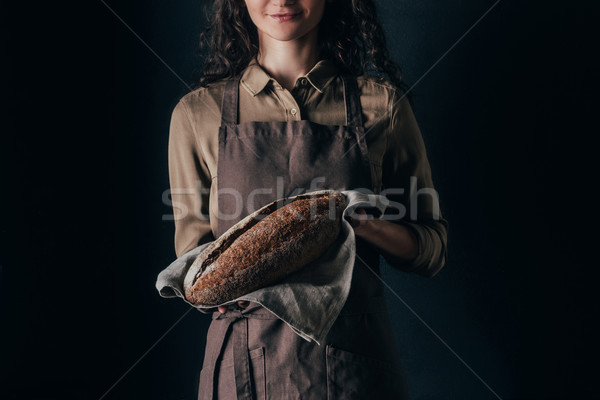 partial view of woman in apron holding french baguette in hands isolated on black Stock photo © LightFieldStudios