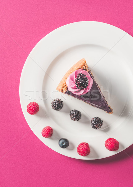 top view of appetizing piece of cake with berries on plate on pink surface Stock photo © LightFieldStudios