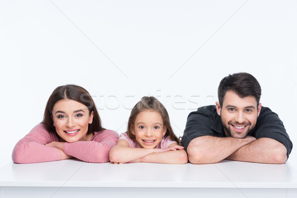 Happy family with one child leaning on white table and smiling Stock photo © LightFieldStudios