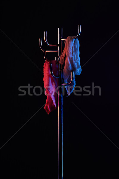 Stock photo: scarf hanging on coat rack under toned light isolated on black