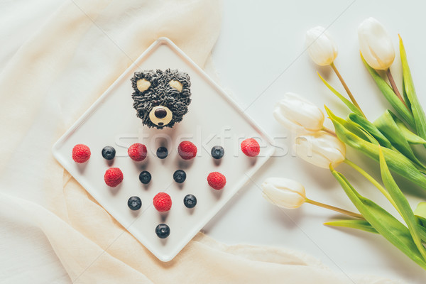 top view of sweet tasty muffin in shape of bear, fresh raspberries and tulip flowers   Stock photo © LightFieldStudios