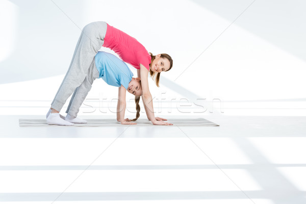 Happy mother and daughter exercising on yoga mat and smiling at camera Stock photo © LightFieldStudios
