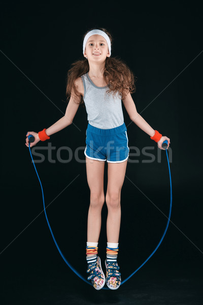 Ragazza abbigliamento sportivo jumping corda isolato nero Foto d'archivio © LightFieldStudios