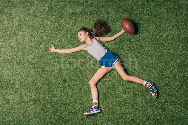 top view of little sportive girl throwing rugby ball on grass, athletics children concept Stock photo © LightFieldStudios