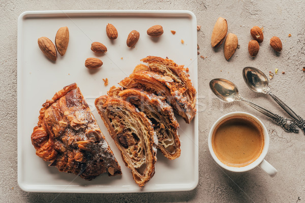 top view of cup of coffee and sweet pastry with almonds on plate on light tabletop Stock photo © LightFieldStudios