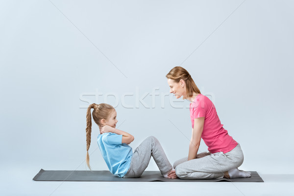 side view of  sporty mother and daughter exercising on mats together on white Stock photo © LightFieldStudios