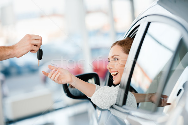 Seller giving key to happy young woman sitting in new car Stock photo © LightFieldStudios