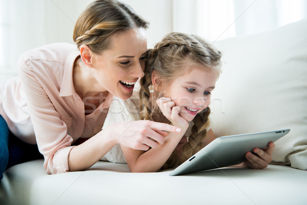 portrait of cheerful mother and daughter using tablet at home Stock photo © LightFieldStudios