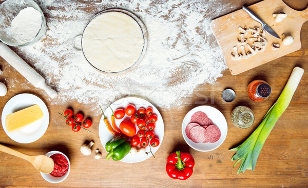 top view of pizza ingredients, tomatoes, salami and mushrooms on wooden tabletop  Stock photo © LightFieldStudios