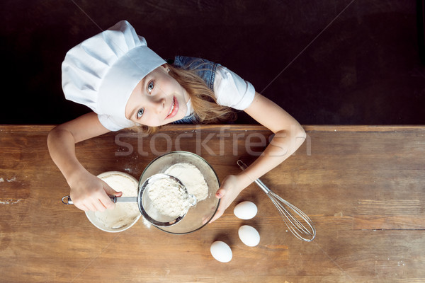 overhead view of girl making dough for cookies on wooden table Stock photo © LightFieldStudios