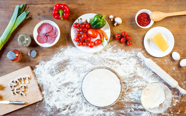 top view of different pizza ingredients, vegetables and dough on wooden tabletop Stock photo © LightFieldStudios