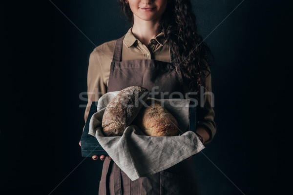 cropped shot of woman holding wooden box with loafs of bread in hands isolated on black Stock photo © LightFieldStudios
