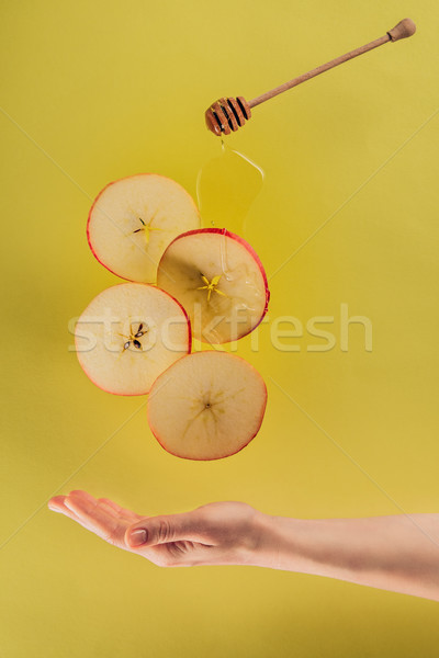 Stock photo: partial view of female hand and levitating pieces of apple with honey