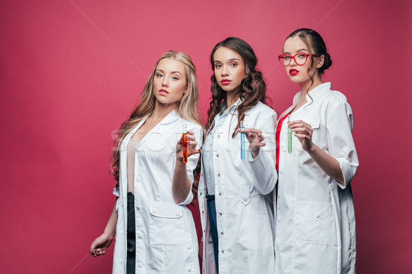 portrait of professional doctors in white coats showing test tubes on pink Stock photo © LightFieldStudios