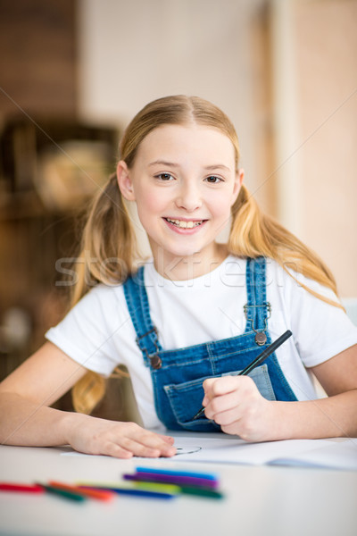 Adorable little girl drawing at table and smiling at camera Stock photo © LightFieldStudios