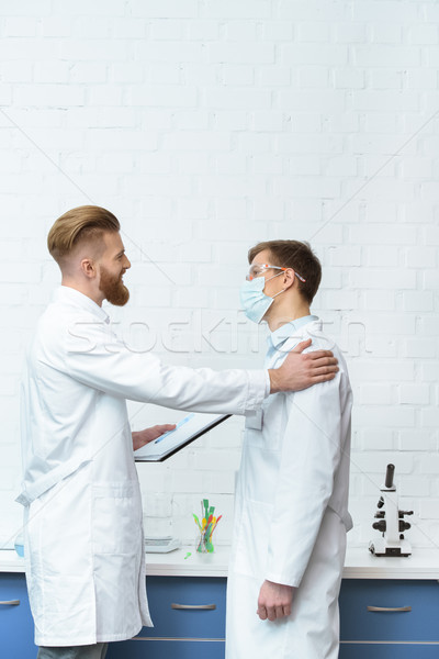 side view of scientists in white coats discussing experiment results in lab Stock photo © LightFieldStudios