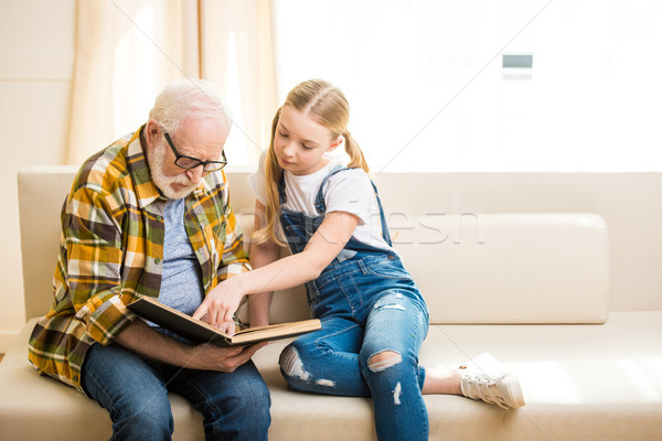 Smiling preteen girl with senior man in eyeglasses reading book together Stock photo © LightFieldStudios